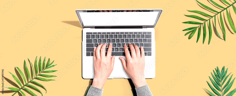 Person using a laptop computer with tropical leaves from above