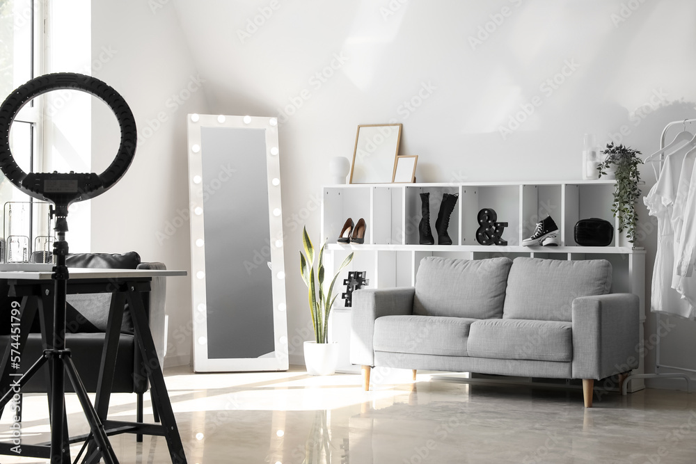 Interior of light makeup room with mirror, shelving unit and sofa