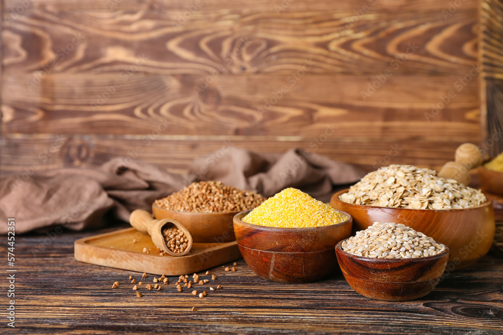 Bowls with different cereals on wooden background