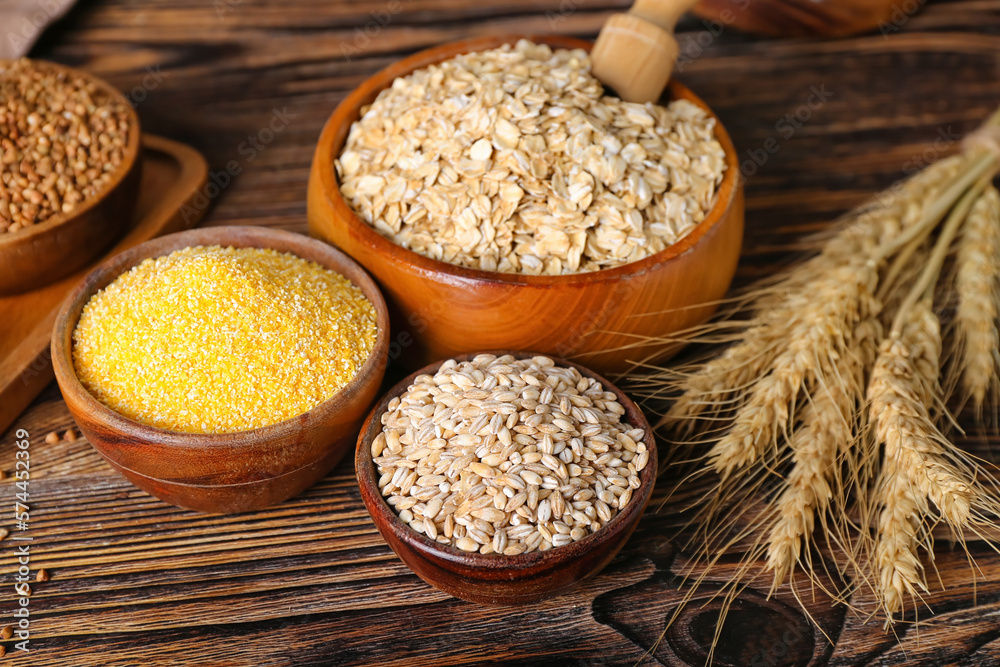 Bowls with different cereals on wooden background