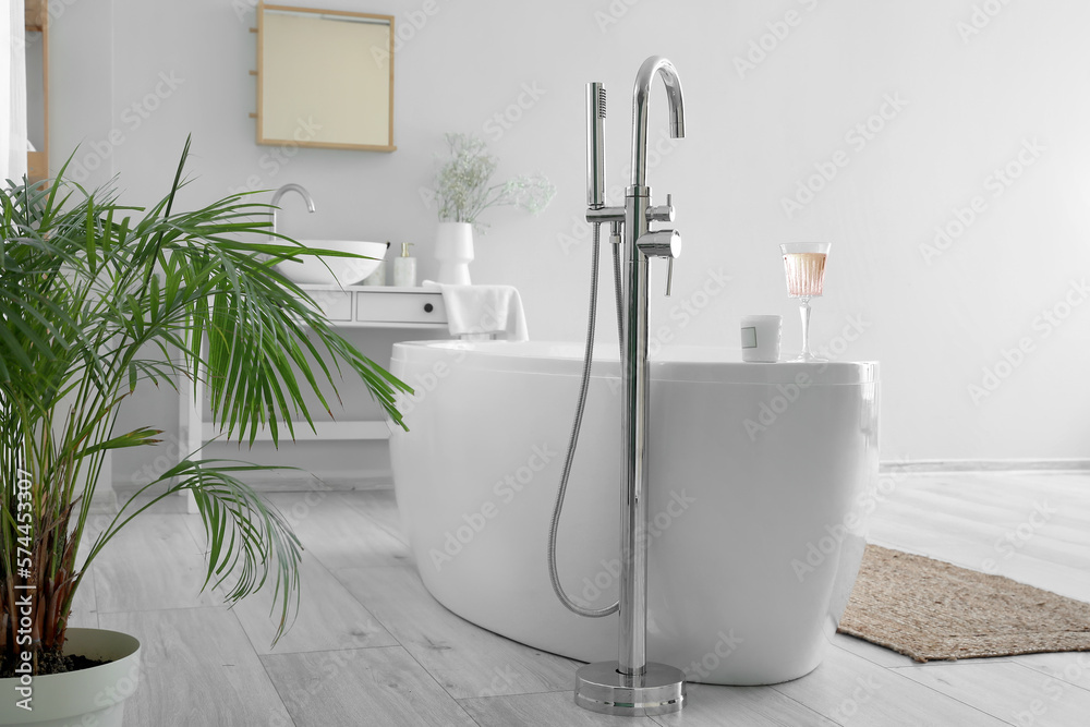 Interior of light bathroom with bathtub, table and sink