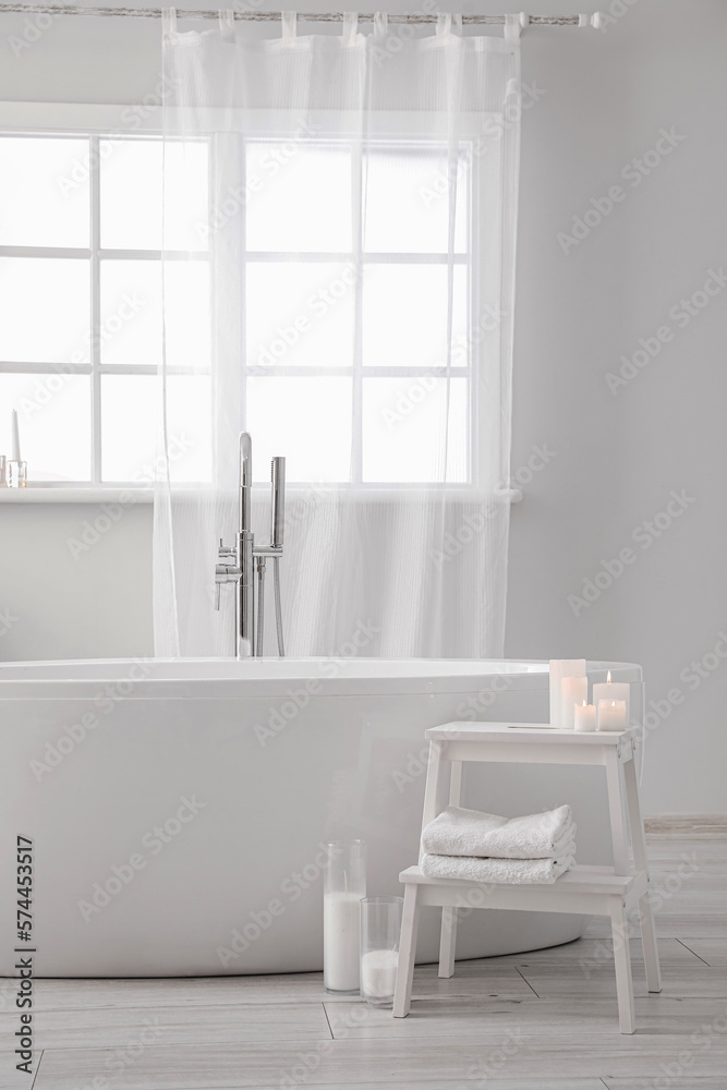 Modern bathtub and table with candles in bathroom interior