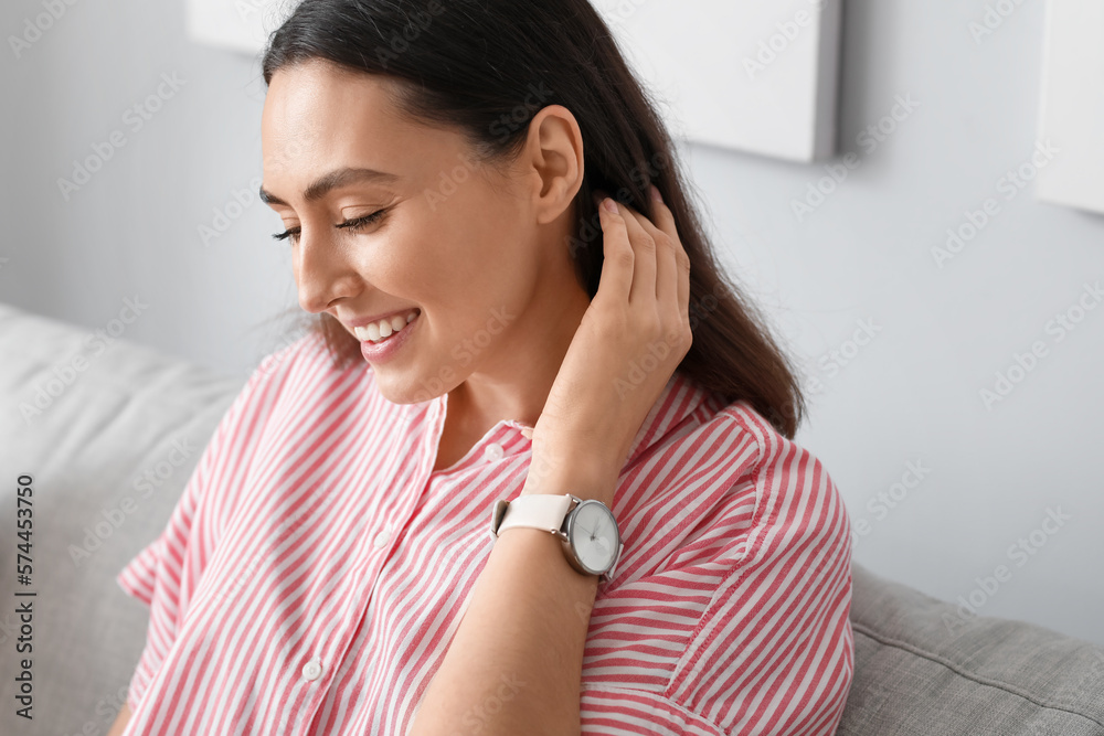 Young woman with stylish wristwatch sitting on sofa at home, closeup