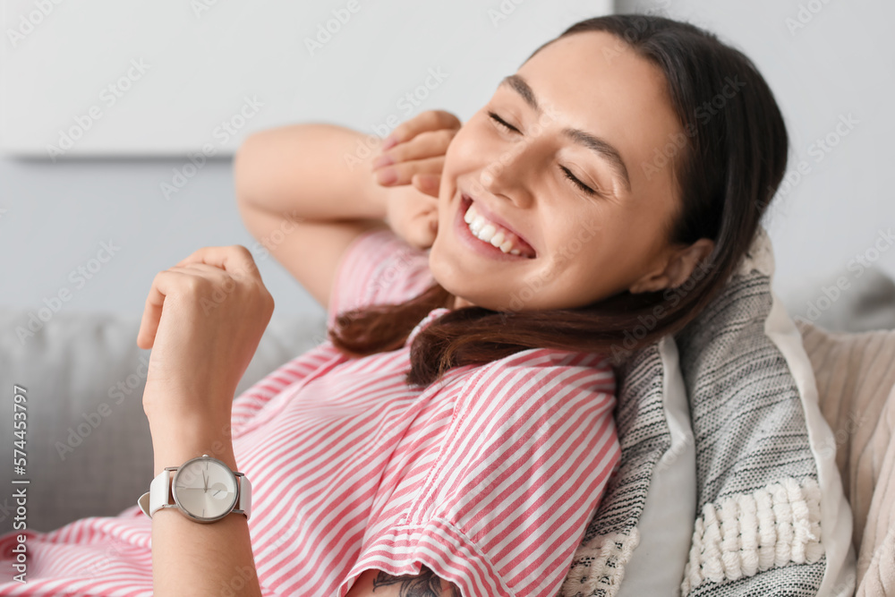 Young woman with stylish wristwatch lying on sofa at home, closeup