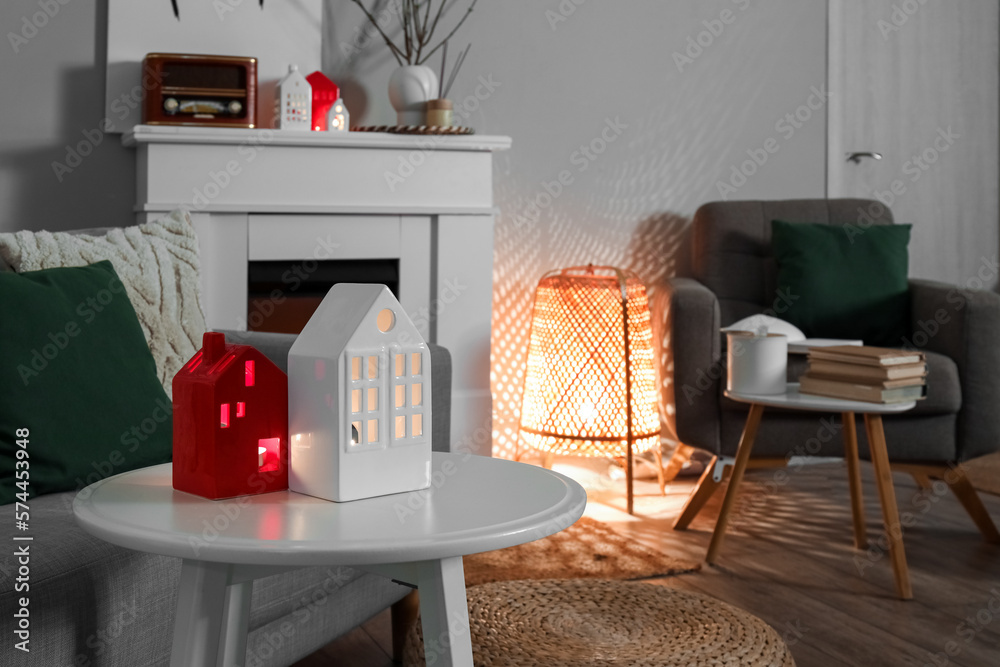 Glowing house candle holders on table in living room, closeup