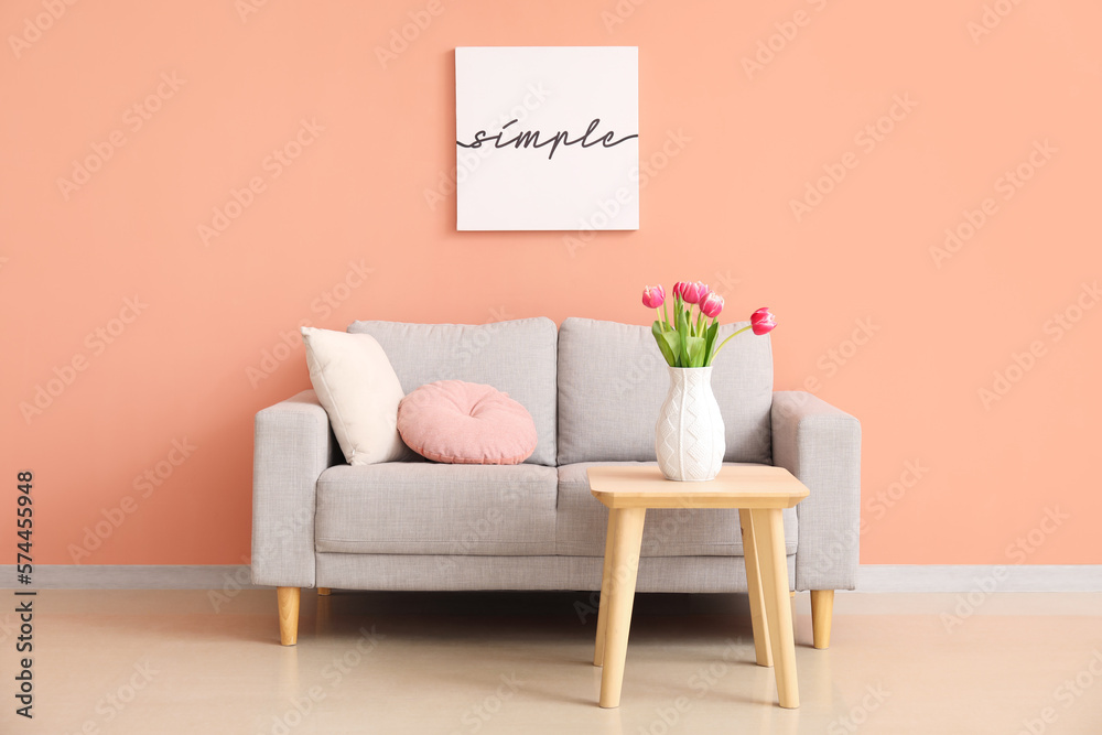 Interior of living room with grey couch and tulips in vase