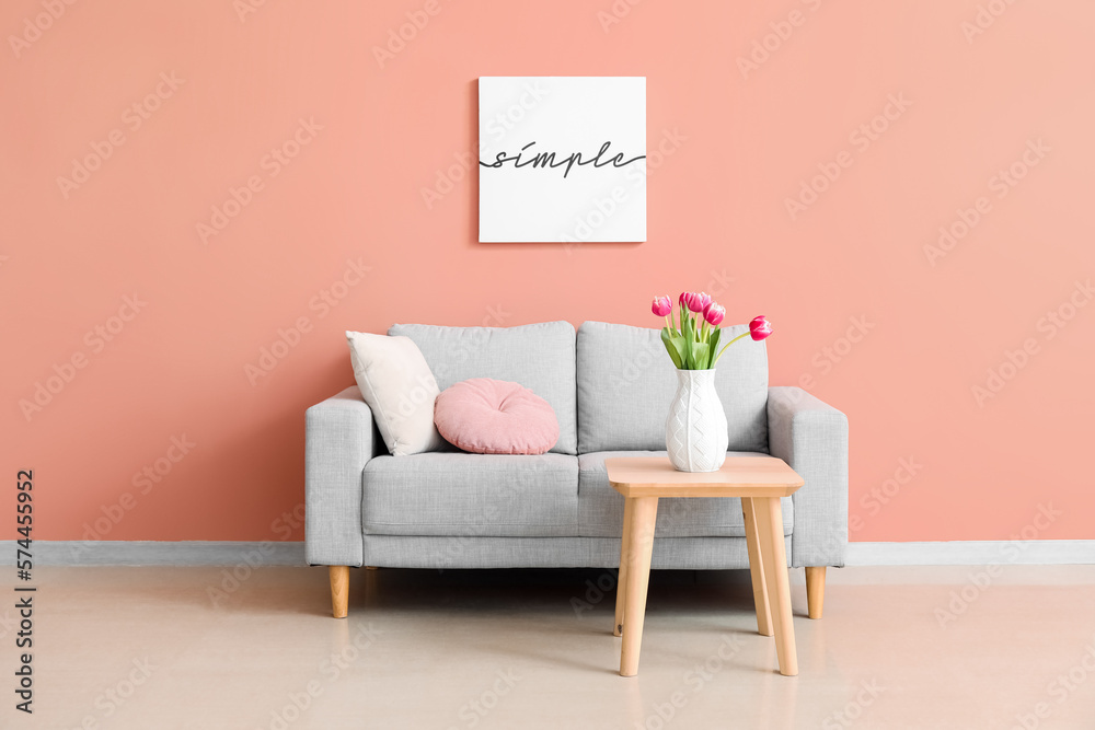 Interior of living room with grey couch and tulips in vase