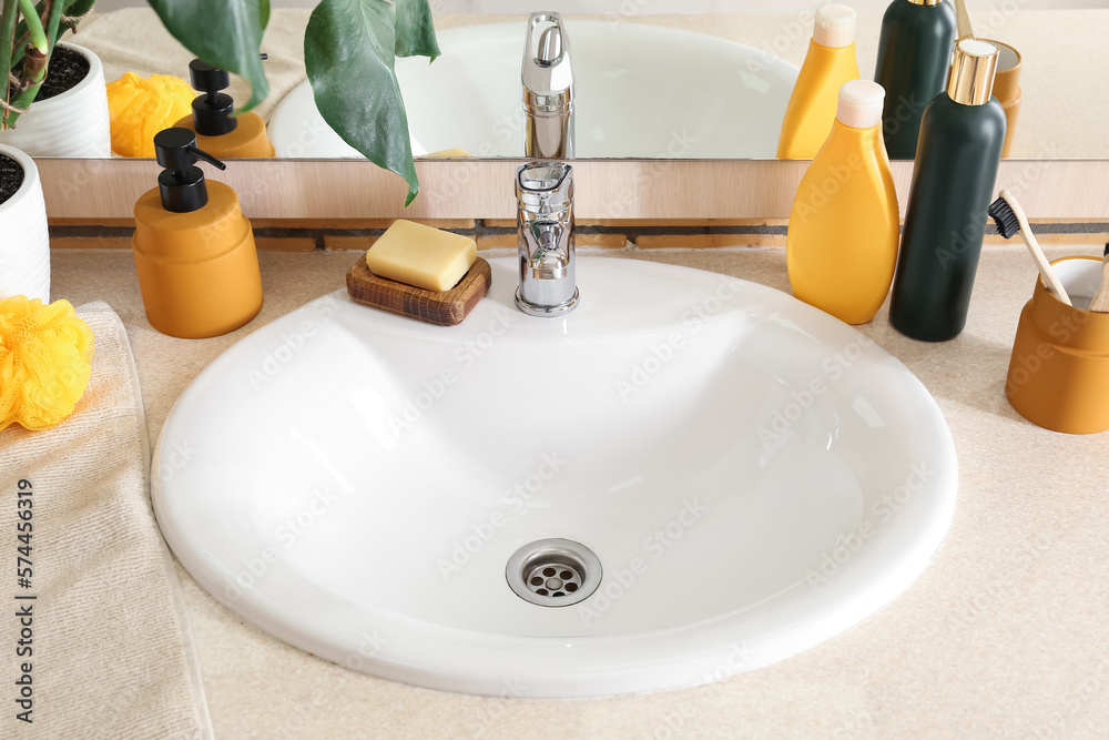 White ceramic sink and bath supplies on table near mirror