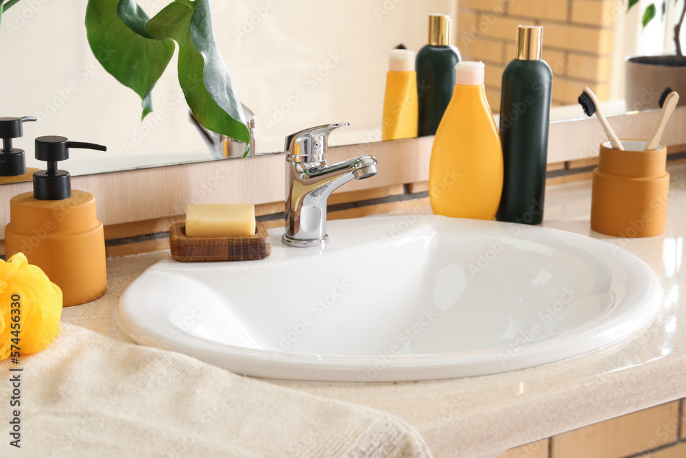 White ceramic sink and bath supplies on table near mirror, closeup