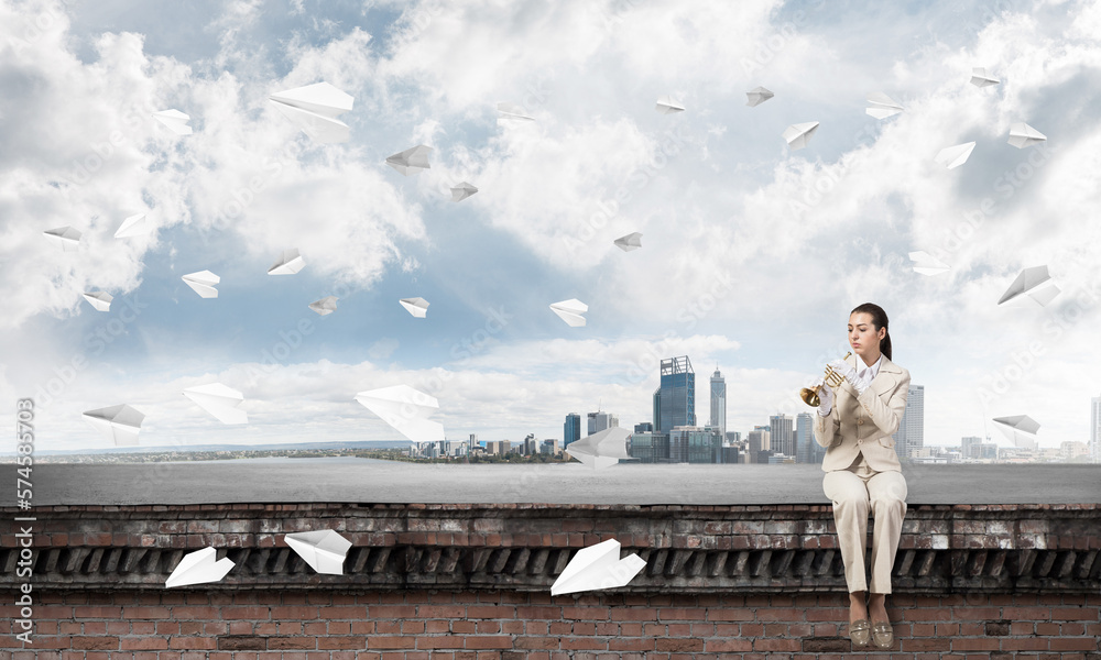 Attractive young woman playing trumpet on roof