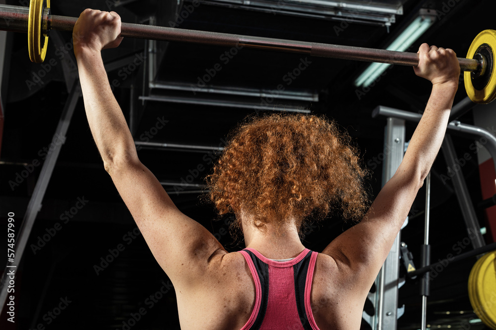 Woman bodybuilder engaged with a barbell in the gym