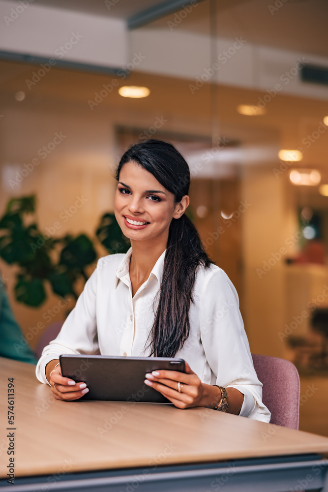 Smiling woman working over the tablet, posing for the camera.