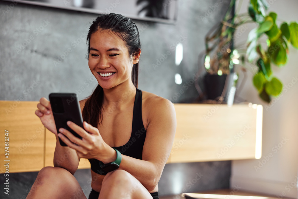 A happy sporty Asian woman having an online video call with a friend over the phone.