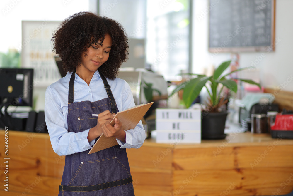 Young African woman small business start-up entrepreneur working in a cafe. Employee working in a co