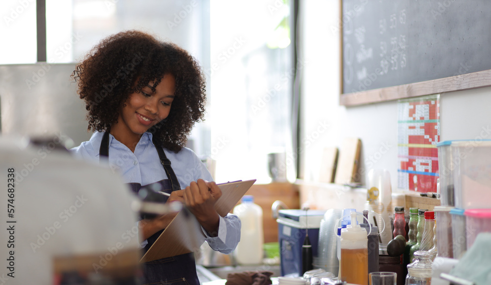 Young African woman small business start-up entrepreneur working in a cafe. Employee working in a co