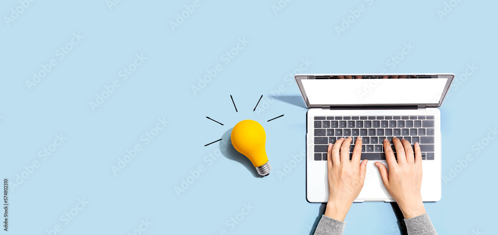 Person using a laptop computer and a light bulb - Flat lay