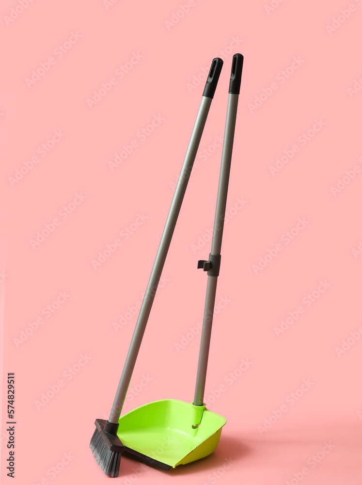 Dustpan with cleaning broom on pink background