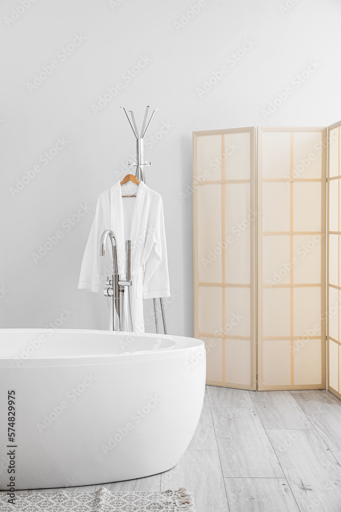 Modern bathtub and rack with bathrobe in bathroom