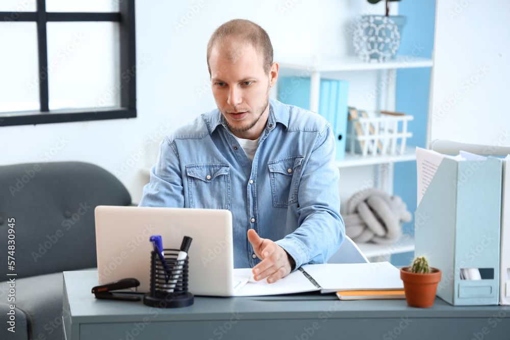 Male tutor with laptop giving online lesson at home