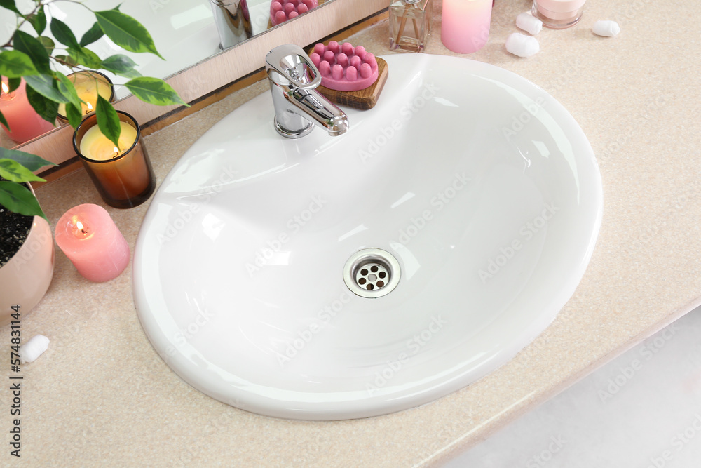 Table with white sink, burning candles and cosmetic products