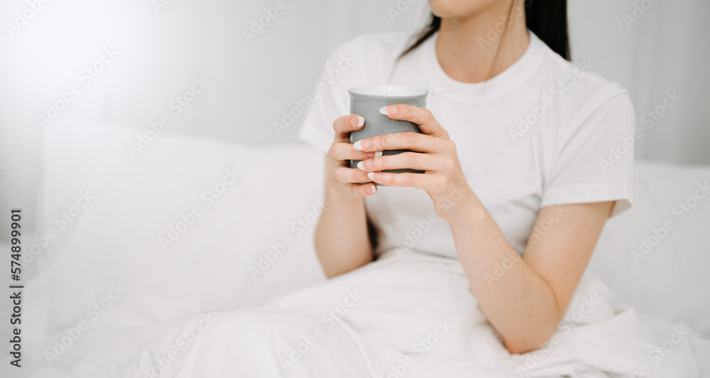 Good Healthy woman drinking tea and resting in white bed at bedroom. Lifestyle at home concept in mo