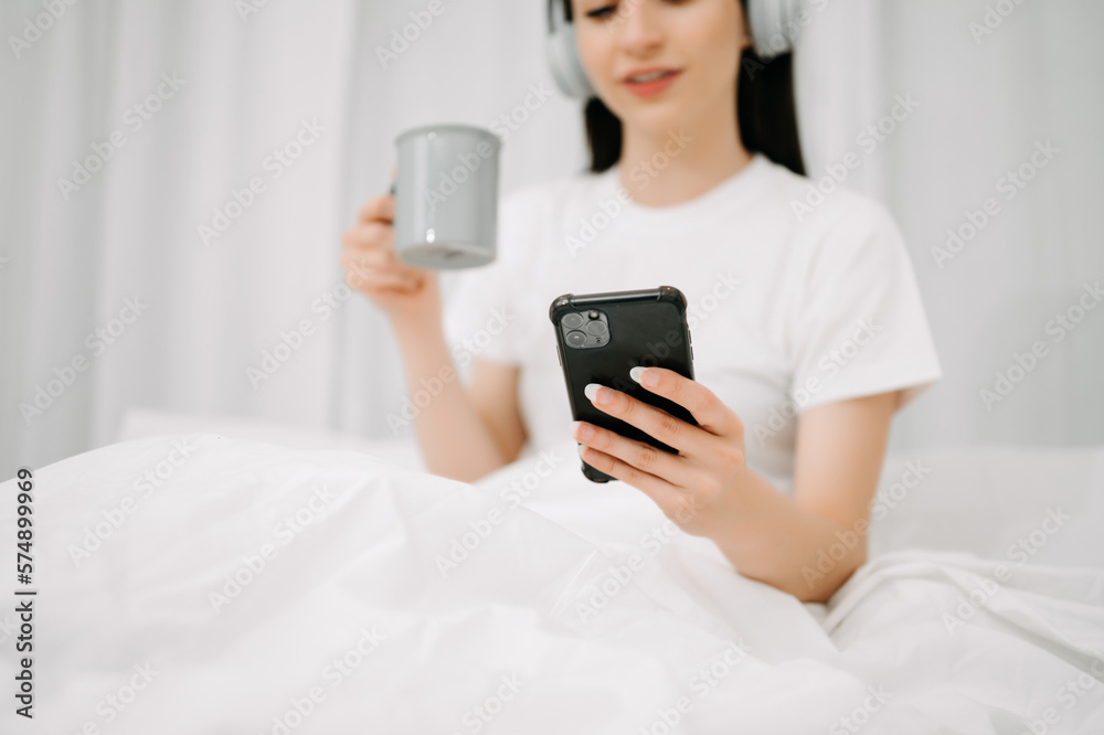 Beautiful woman has woken up on a white bed and holding coffee in the morning at home in morning