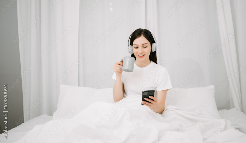 Beautiful woman has woken up on a white bed and holding coffee in the morning at home in morning