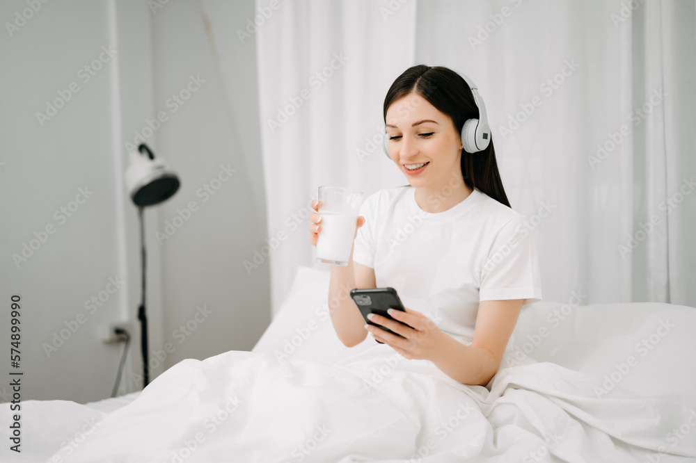 Beautiful woman has woken up on a white bed and holding coffee in the morning at home in morning