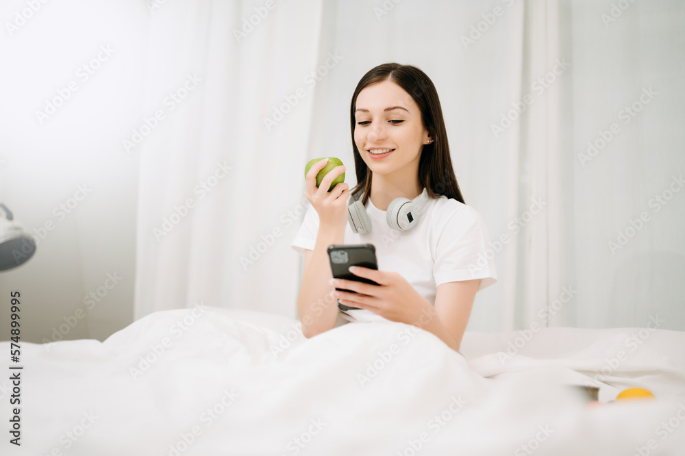 Beautiful woman has woken up on a white bed and holding coffee in the morning at home in morning