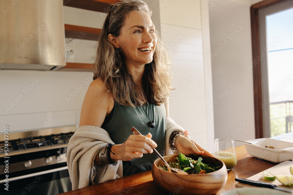 Happy mature woman having a healthy vegan meal at home