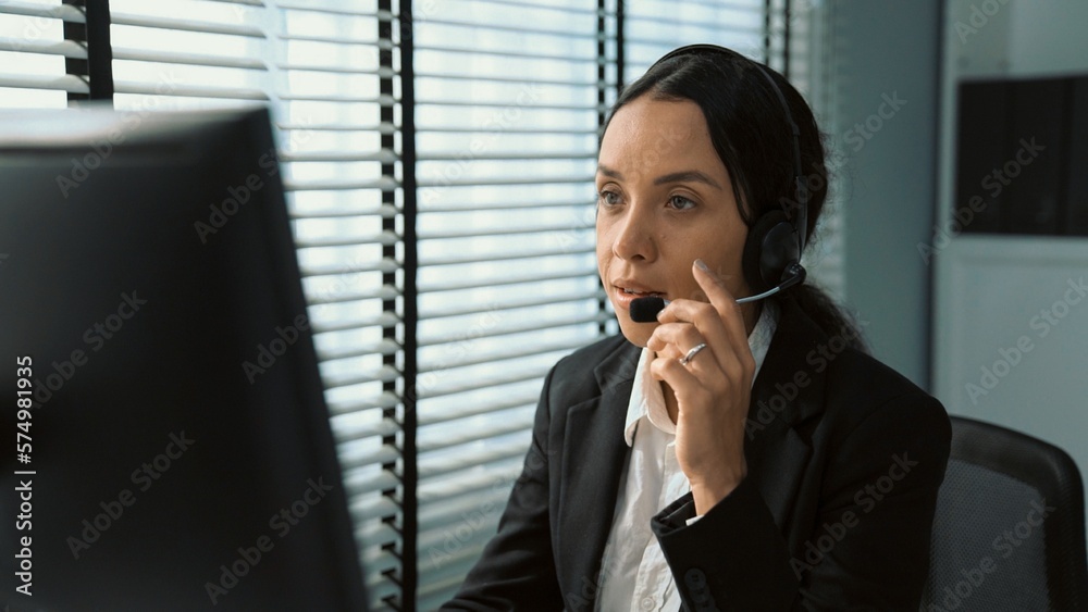 Competent female operator working on computer and talking with clients. Concept relevant to both cal