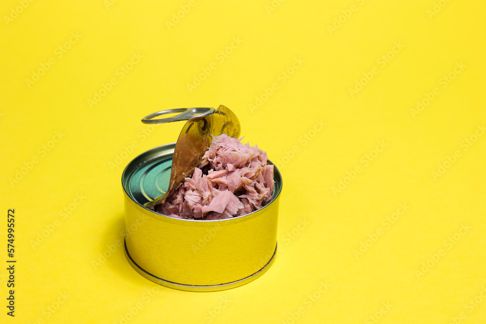 Closeup top view open can of preserve food, tuna flakes in round golden cans isolated on yellow back