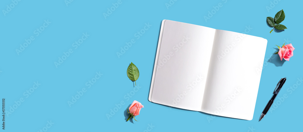 Open notebook or diary with a pen from above with rose buds- flat lay