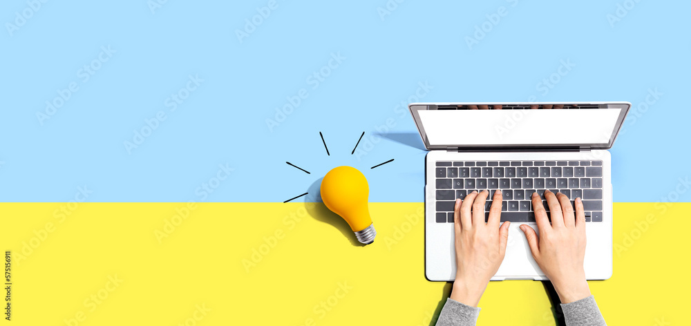 Person using a laptop computer and a light bulb - Flat lay