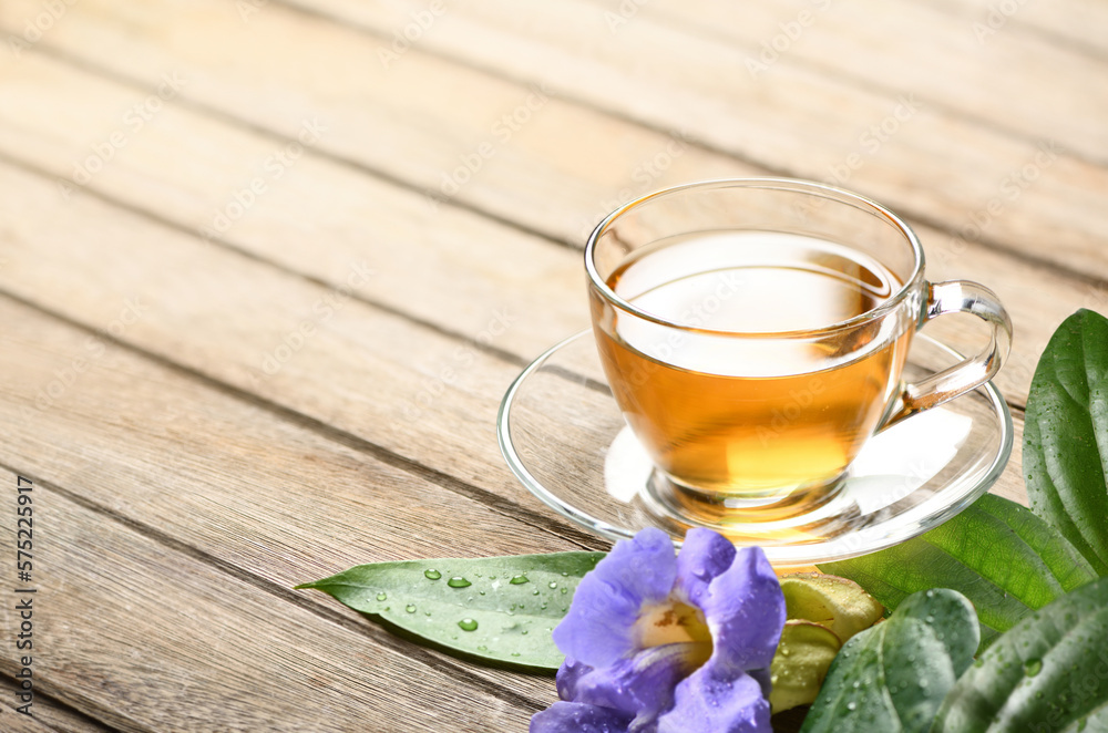 Laurel clock vine (Thunbergia laurifolia) tea with flower and leaves on wooden table.