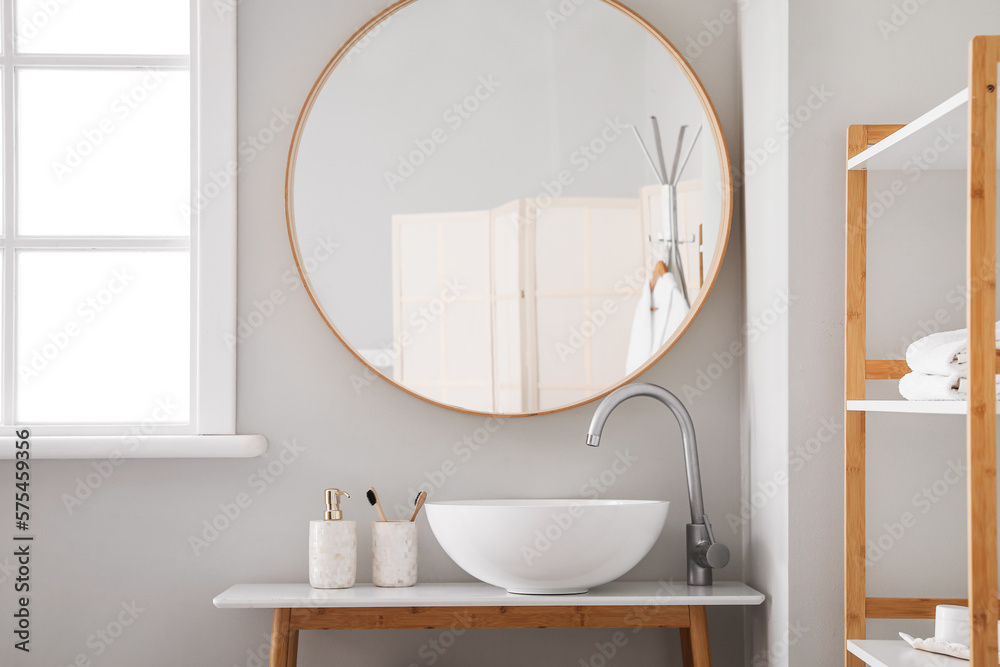 Table with modern sink, mirror and accessories in bathroom