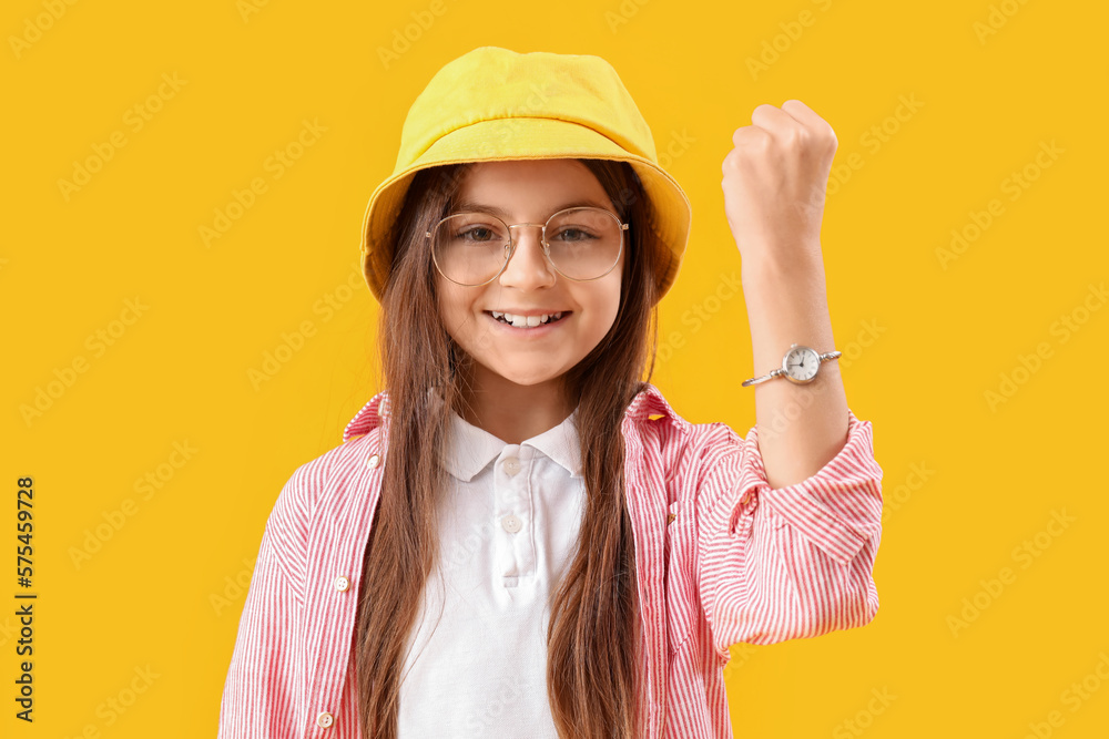 Little girl with wristwatch on yellow background