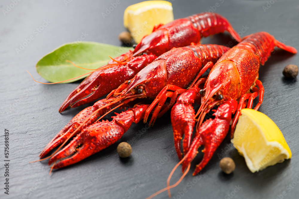 Crayfish, clawfish, crawfish closeup. Red boiled crayfishes with herbs and lemon on stone slate dark