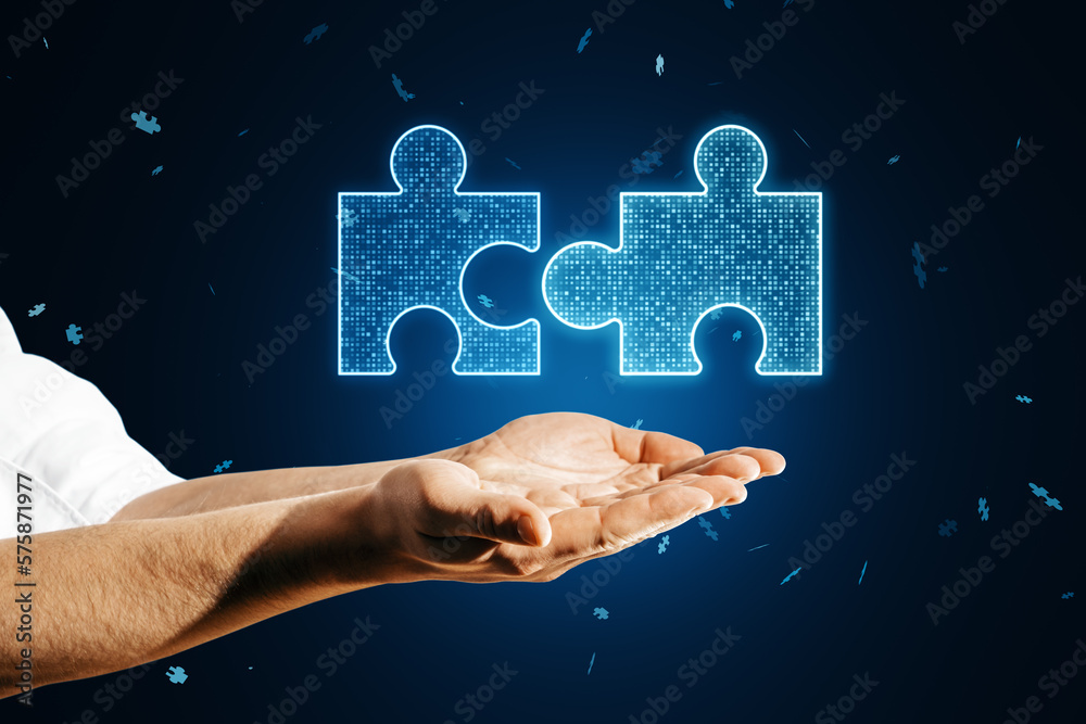 Close up of male hands holding glowing digital blue jigsaw puzzle hologram on dark blurry background