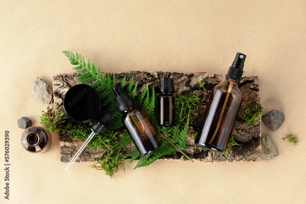 Unlabelled cosmetic bottles on natural beige background, natural moss over branches, bark. Skin care