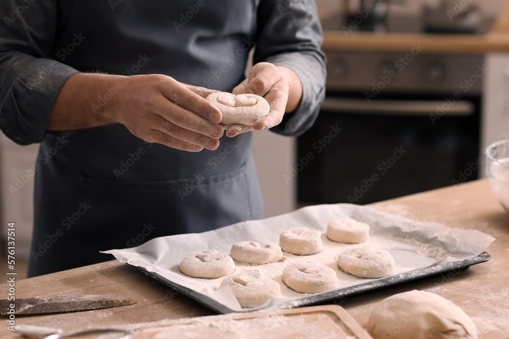 Male baker making buns at table in kitchen, closeup