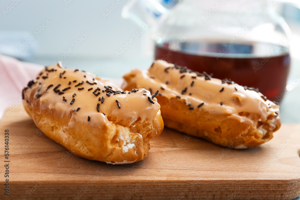 Board with delicious eclairs on grey table