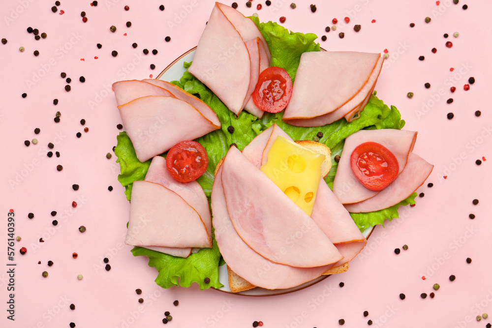 Plate with tasty slices of ham, cheese, lettuce and tomatoes on pink background