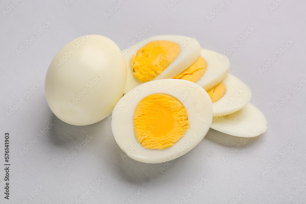 Slices of delicious boiled eggs on grey background