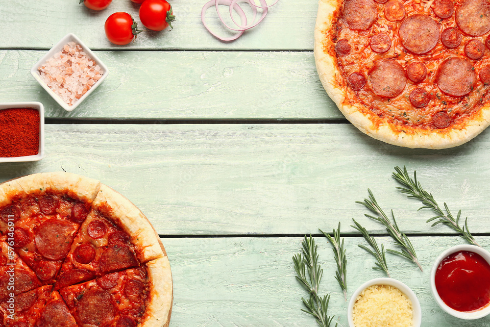 Frame made of delicious pepperoni pizzas and ingredients on green wooden background