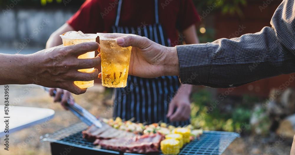 Cheers! Group of young male friends drinking beer at outdoor barbecue party at home.