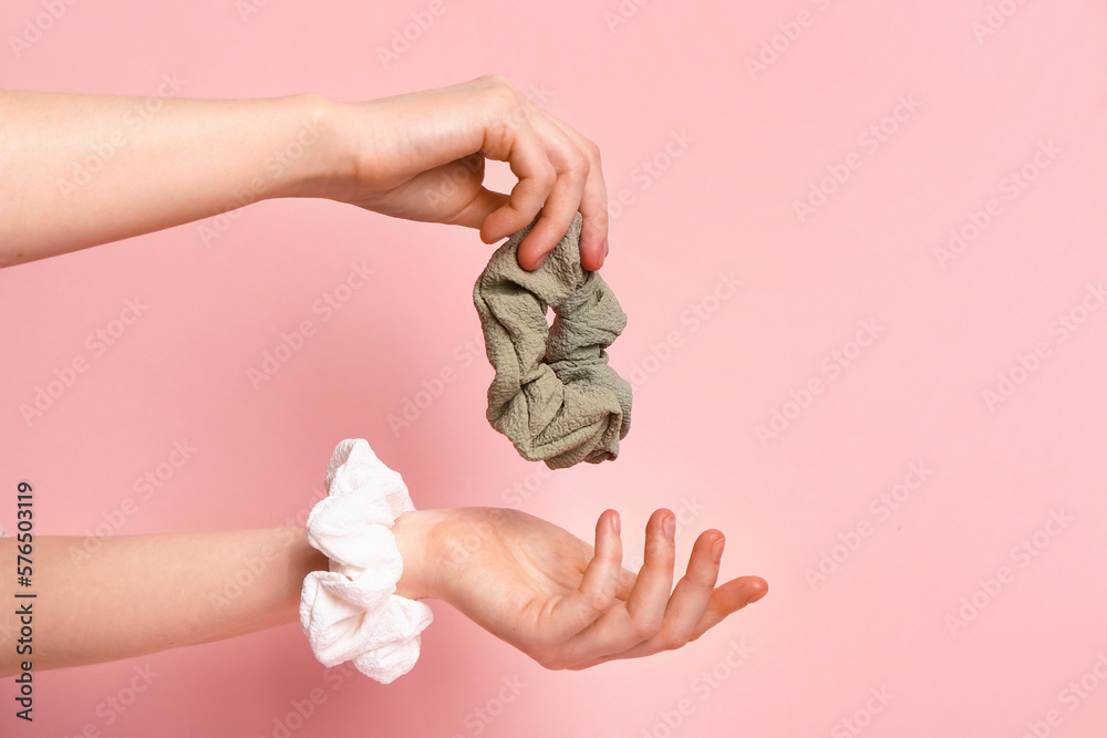 Female hands with stylish scrunchies on pink background