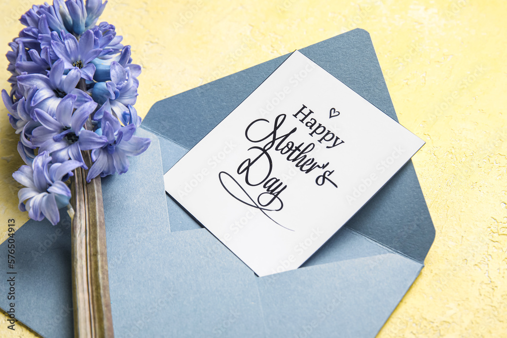 Card with text HAPPY MOTHERS DAY, envelope and beautiful hyacinth flower on yellow background, clos