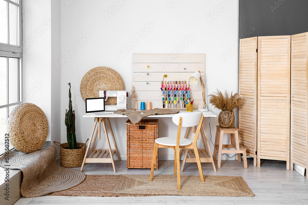 Interior of modern atelier with tailors workplace, poufs and folding screen