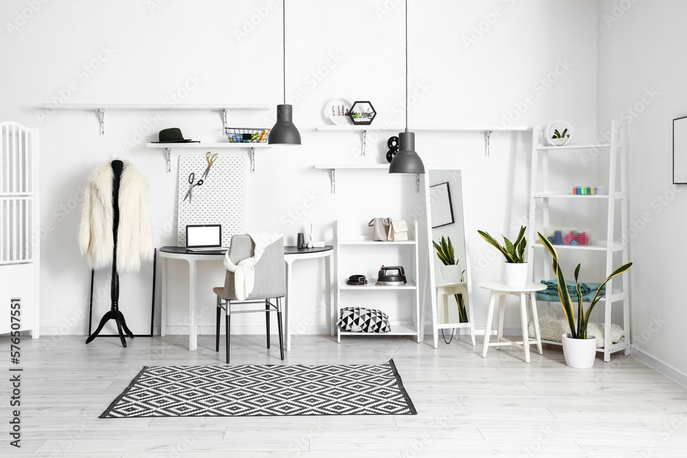 Interior of modern atelier with tailors workplace, shelving units and mirror